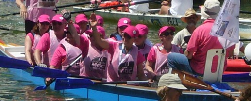 Des bénévoles de l'association, vêtus de maillots et de casquettes roses, saluent le public depuis leur aviron lors du défi de la Vogalonga.